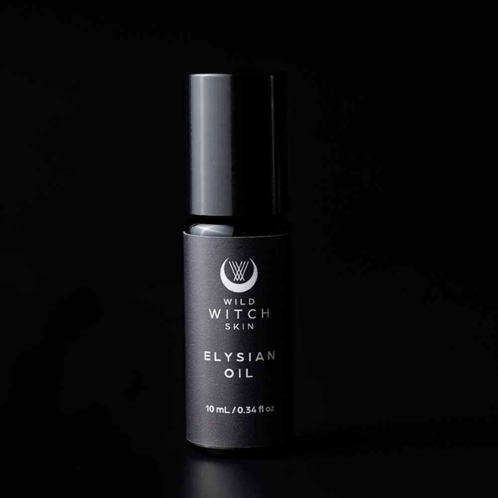 A 10 mL black bottle of Wild Witch Skin Elysian Oil, featuring a matching black cap, set against a solid black background with a subtle reflection below.