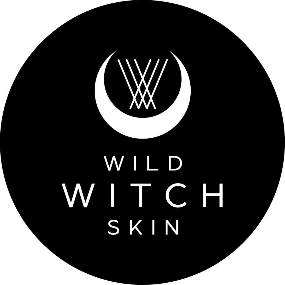 A circular black logo with a white crescent moon and stylized 'W' emblem above the words 'WILD WITCH SKIN'.